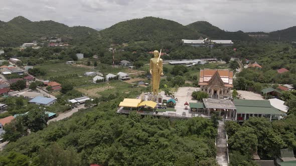 Aerial view of Buddhist temple at lush Hilltop,  Standing Golden Buddha Statue