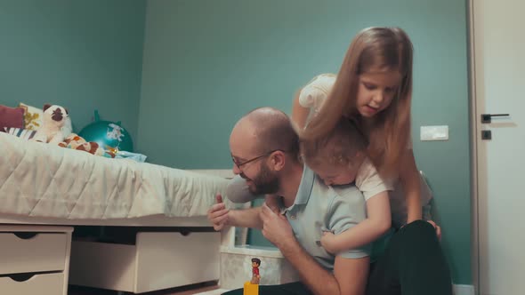 Happy young dad plays at home with his two daughters. 