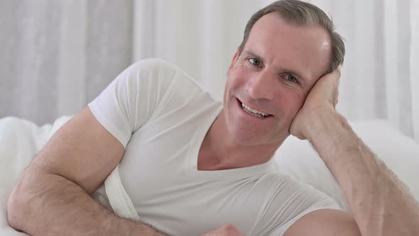 Close Up of Middle Aged Man Smiling at the Camera in Bed 