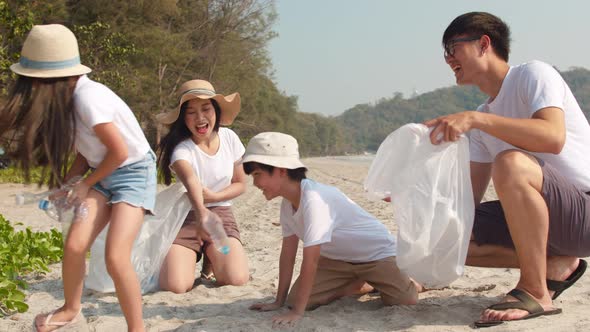 Asian young happy family activists collecting plastic waste on beach.
