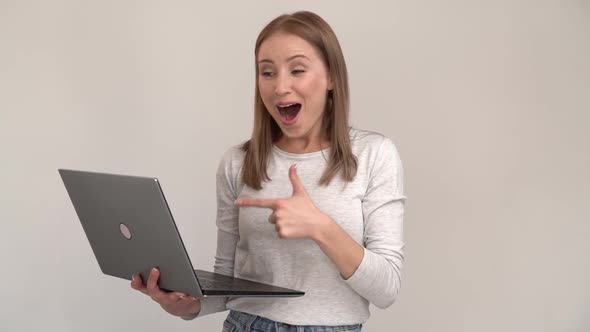 Wow. Surprised happy excited woman looking with amazement into laptop screen