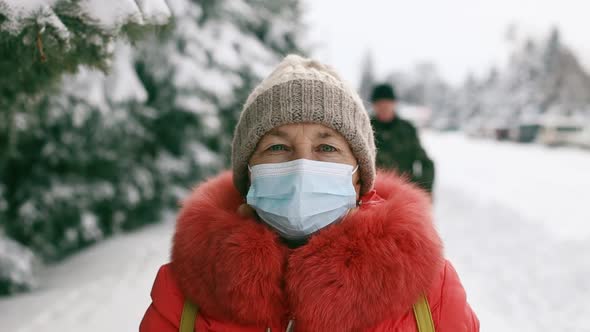 Adult Senior Woman in Protective Medical Mask Looking at the Camera in the Winter Park