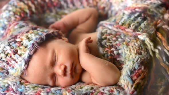 Newborn Baby Sleeps in a Knitted Scarf