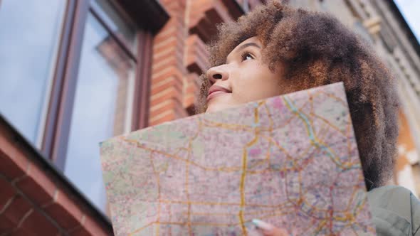 Young Attractive African American Black Female Tourist with Paper Map Walks in Center of City on