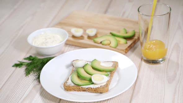 A Woman Is Making a Toast with Cream Cheese Avocado and Quail Eggs
