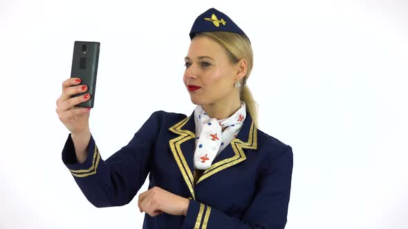 A Young Beautiful Stewardess Takes Selfies with a Smartphone - White Screen Studio