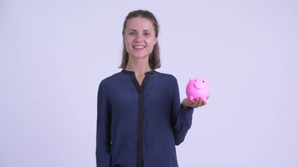 Happy Young Beautiful Businesswoman Holding Piggy Bank and Giving Thumbs Up