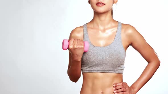 Slim perfect female body in sportswear holding dumbbell on white background