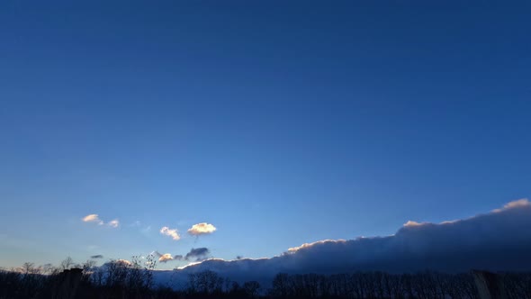 Time lapse dark clouds obscure the evening sun at sunset, and clear blue skies