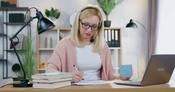 Woman in Glasses Working at Home Desk with Documents and Computer Information