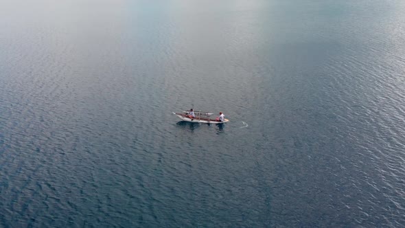 Two Males Paddling in Traditional Boat With Outrigger on Calm Surface of Tropical Sea, Drone Aerial