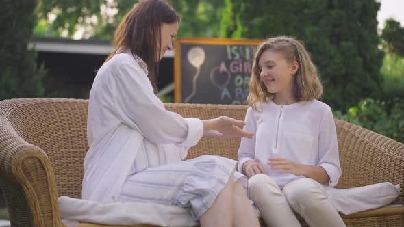 Side View Smiling Pregnant Mother Holding Hands with Teenage Daughter Talking in Slow Motion