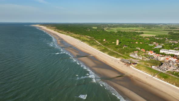 Aerial shot of changing tides outside a picturesque little coastal town in a green, rural area, on a