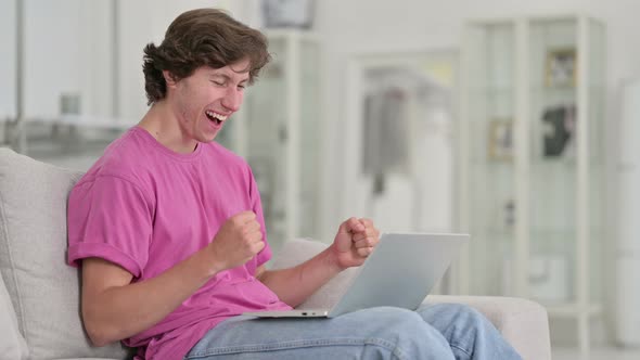 Excited Casual Young Man Celebrating Success on Laptop at Home 