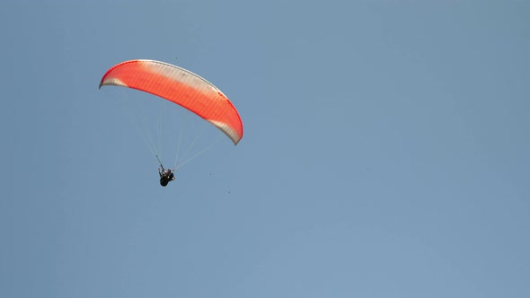 Red parachute flying against clear blue sky. 