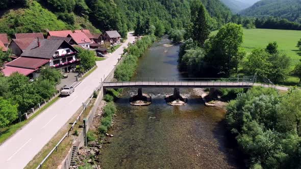 Flying above a river near a bridge in Osilnica in Slovenia, Europe. It is a quiet and sunny day duri