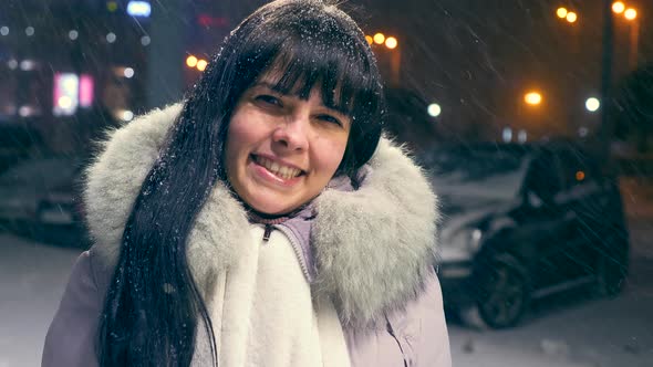 Beautiful Girl Smiling Winking Her Eye Blows Kiss. Young Adult Under Heavy Snowfall.