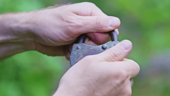 Closeup of a Caucasian Man is Closing an Old Padlock with Hands