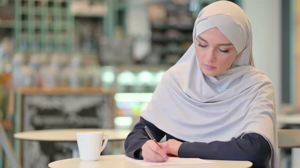 Serious Young Arab Woman Writing on Paper