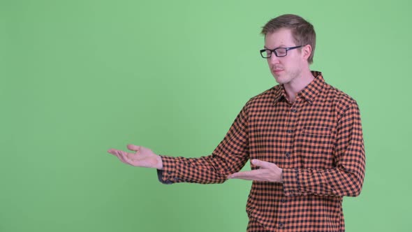 Young Handsome Hipster Man Showing Something and Giving Thumbs Up