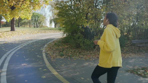 Girl Running on Track at the City Park in Sunny Autumn Morning Using Headphones