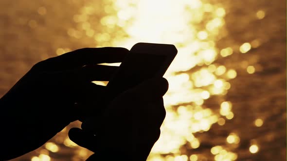 Silhouette of the Man Using Smart Phone Beside the Reservoir with Sunset - Slow Motion