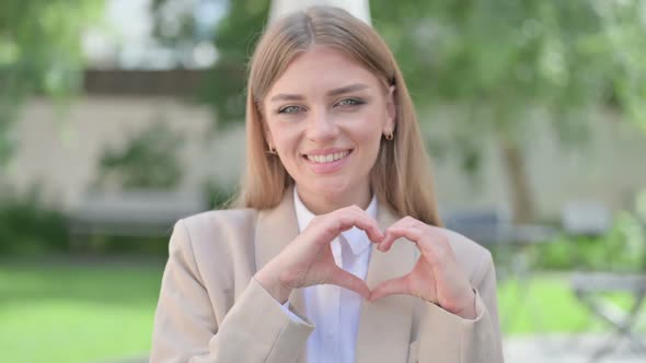 Outdoor Portrait of Young Businesswoman Making Heart Shape with Hands