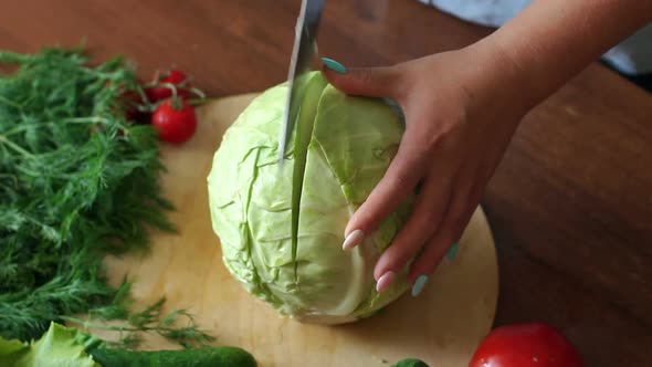 Closeup of a Woman Cuts a Knife in Half Cabbage on a Cutting Board