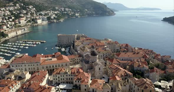 Aerial footage of Old Town in Dubrovnik, the camera passes over Dubrovnik Cathedral and Port showing