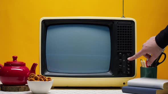 Closeup of Old Retro Television on Orange Background Pressing Buttons