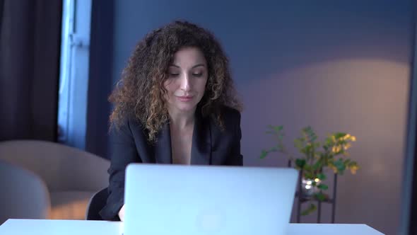Business Woman in a Black Business Suit Works in the Office with a Laptop