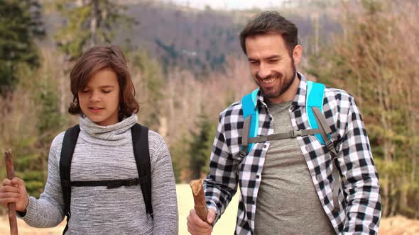 Happy father and his teenage son hiking in the forest