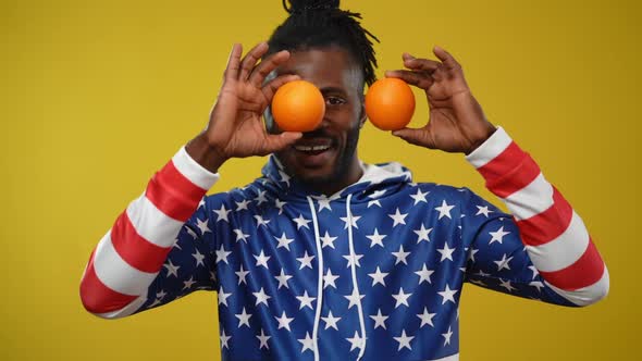 Handsome Cheerful African American Man Having Fun Posing with Oranges at Yellow Background
