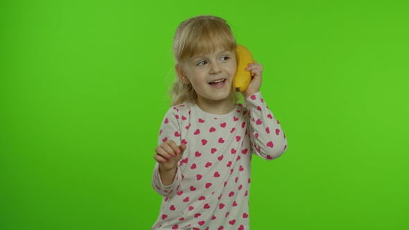 Happy Child Girl Kid Imitating Telephone Conversation with Banana Isolated on Chroma Key Background