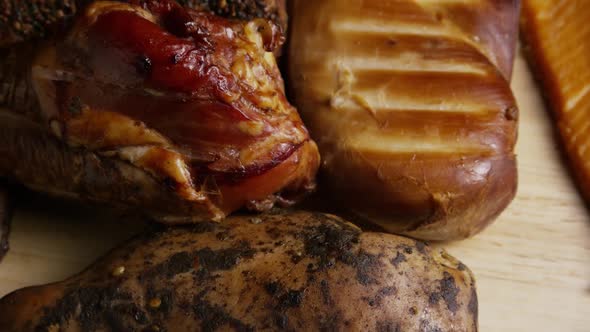 Rotating shot of a variety of delicious, premium smoked meats on a wooden cutting board