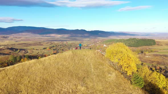 Flying Over a Hiking Woman Relaxing on a Mountain Peak. Aerial View by Drone