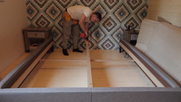 A Worker Builds a Bed in the Bedroom