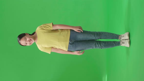 Full Body Of Smiling Asian Kid Girl Positively Shaking Her Head At The Camera In The Green Scree alt