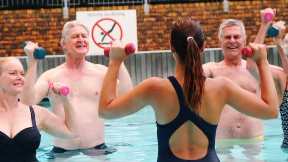 çSwim trainer assisting seniors in performing exercise