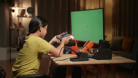 Girl Is Working With Desktop Computer And Looking At Mainboard In Home, Mock Up Green Screen Display