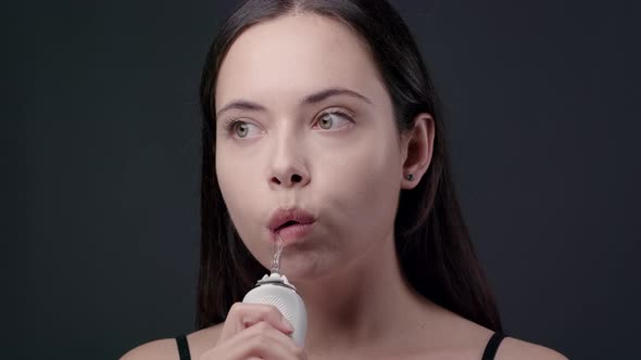 Young Brunette Woman Cleaning Her Teeth with Water Flosser