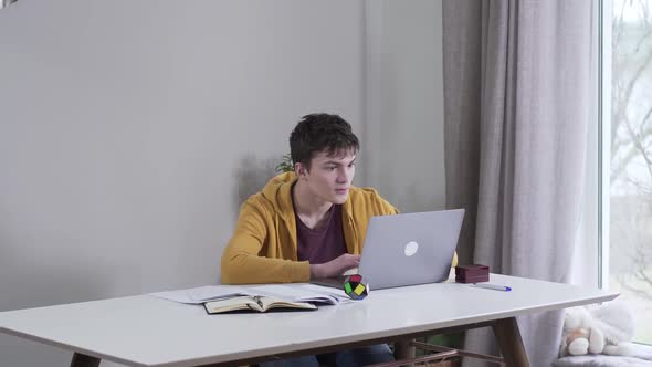 Portrait of Absorbed Caucasian Boy Gaming As Mother Putting Stack of Book on Table Angrily and