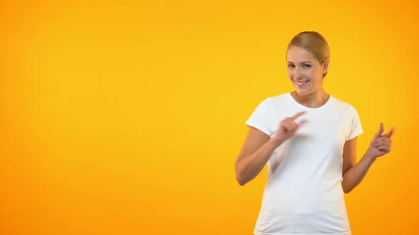 Attractive Female Pointing Fingers on Orange Background, Template Presentation