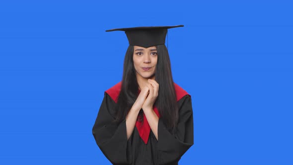 Portrait of Female Student in Graduation Costume Looking at Camera with Excitement Then Sighs in
