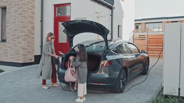 Mother and Daughter Taking Bags out of Car Trunk