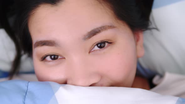 Closeup of Female Smiling and Looking at Camera and lovely Lies in Bed Covered with Blanket.