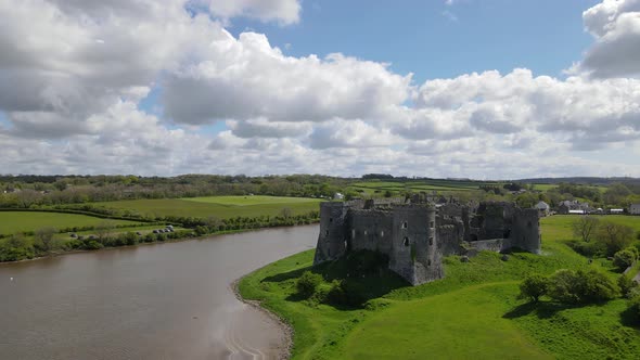 Riverside Carew Castle and green shores, Wales. Aerial drone descending