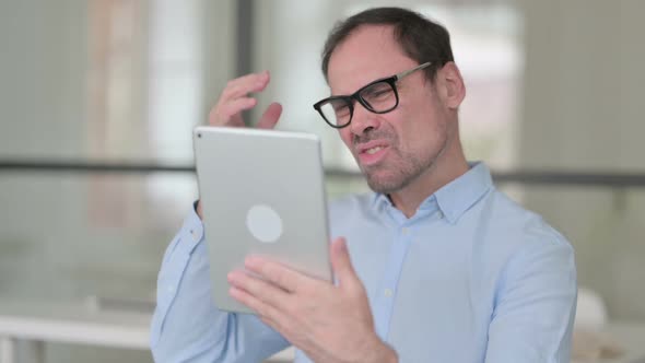 Middle Aged Man Having Loss on Tablet in Office