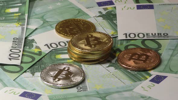 Gold Bit Coin BTC Coins Rotating on Bills of 100 Euro Banknotes. Worldwide Virtual Internet