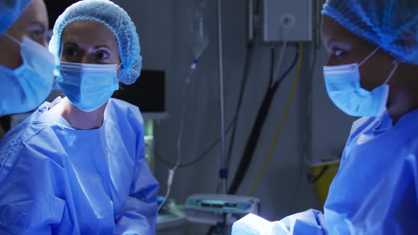 Diverse surgeons wearing surgical caps and face masks in operating theatre in hospital